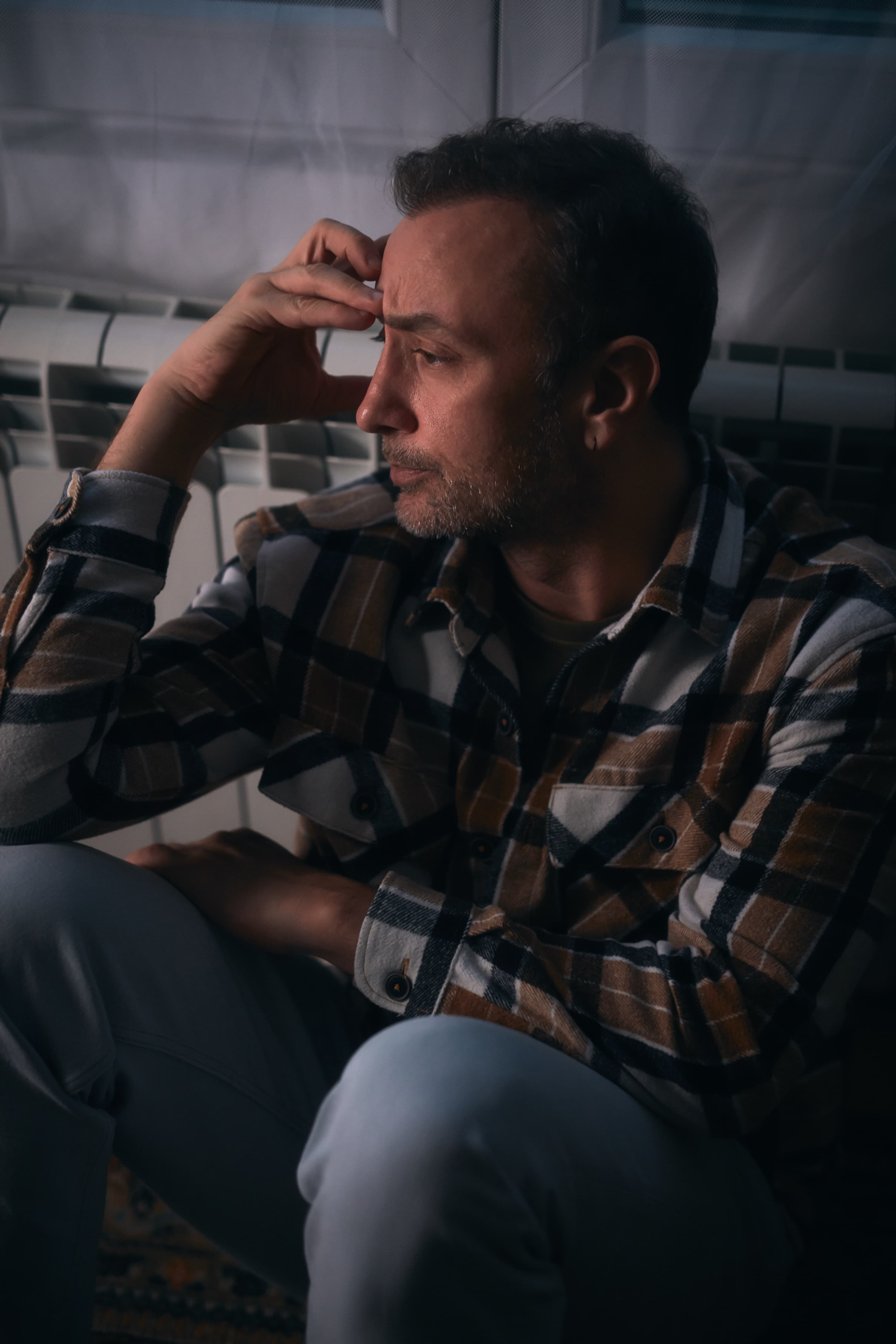 चिंतित व्यक्ति फर्श पर बैठा है